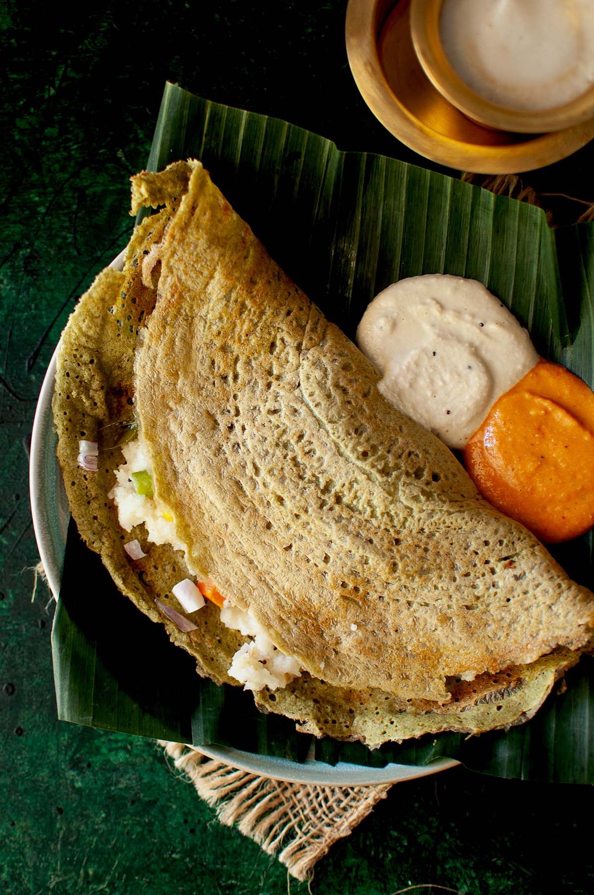 Banana leaf covered plate with Pesarattu upma and chutneys.