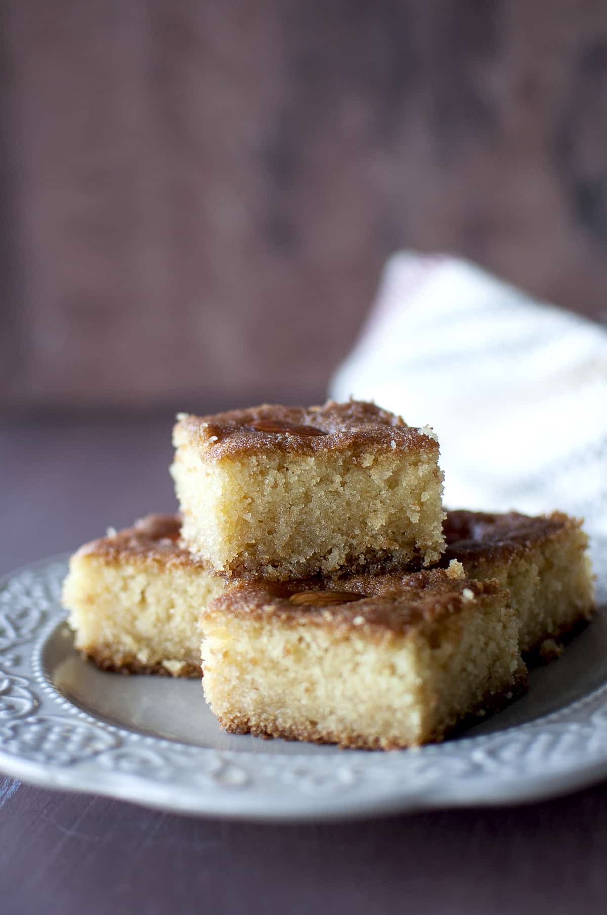 Grey plate with a stack of namoura squares topped with almonds.