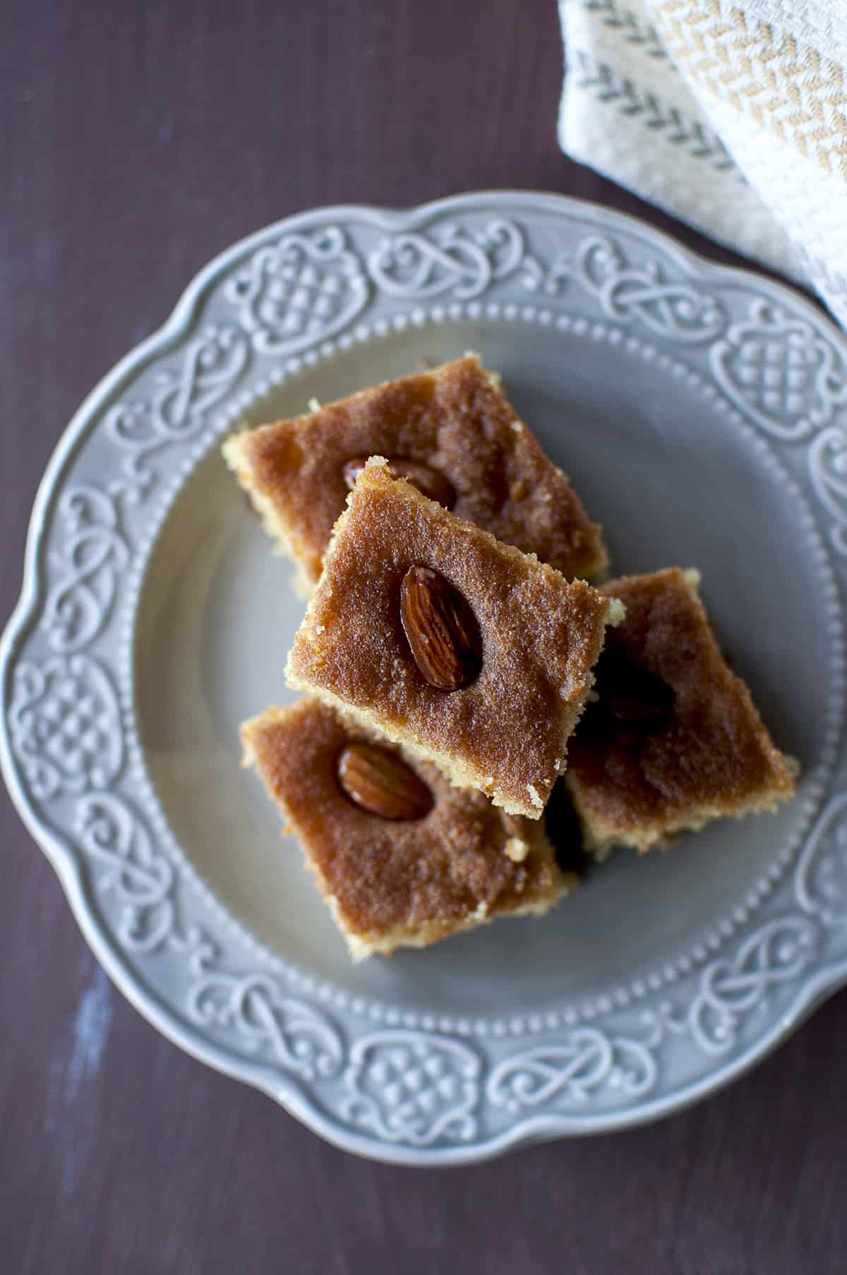 Grey plate with a stack of semolina cake squares topped with almonds