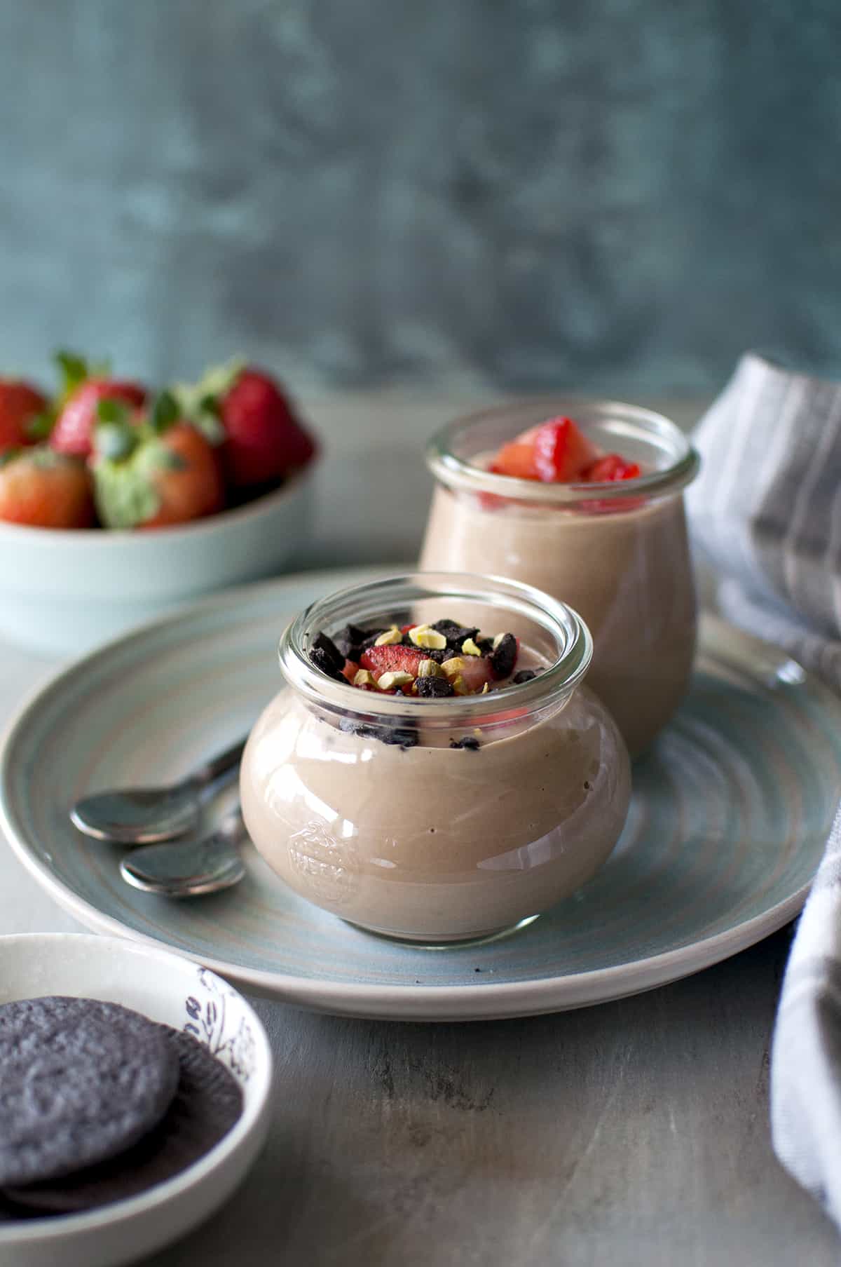 Chocolate custard topped with chopped berries, crushed cookies and nuts in a glass bottle