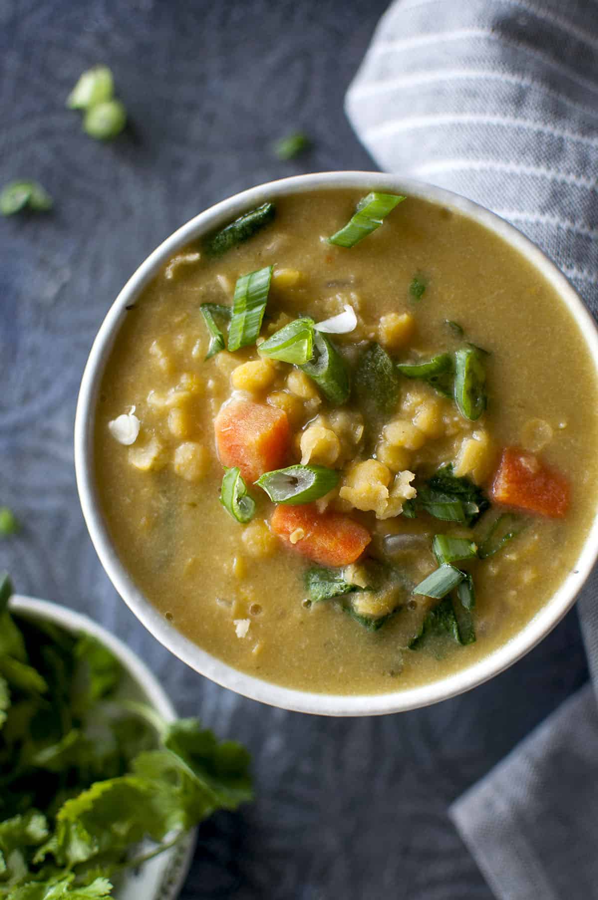 White bowl with Thai split pea soup sprinkled with chopped green onions