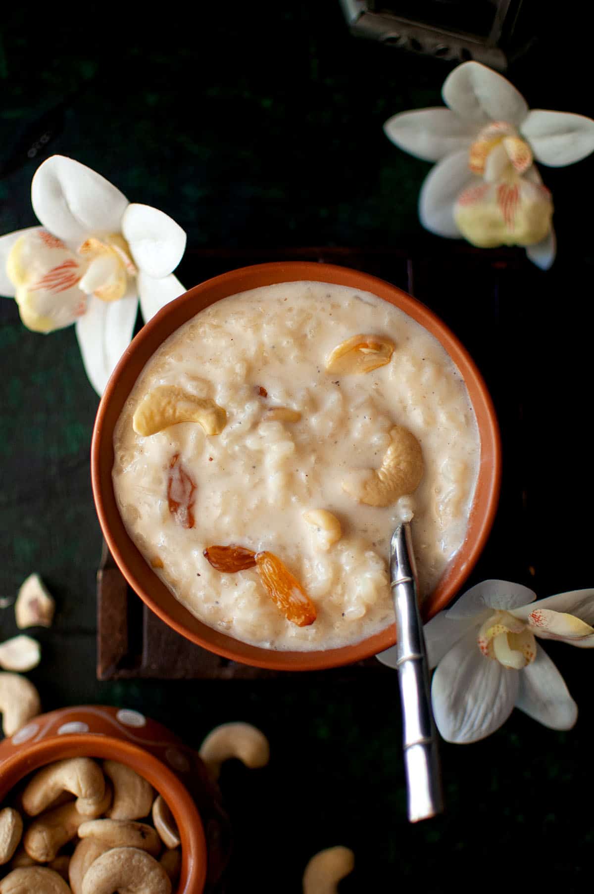 Bowl with rice kheer and a spoon on the side.