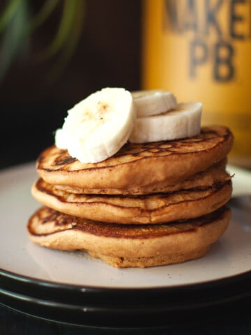 White plate with a stack of peanut butter pancakes.